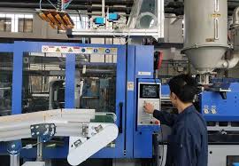 Operator injection molding melakukan pengecekan kualitas produk plastik di samping mesin injection