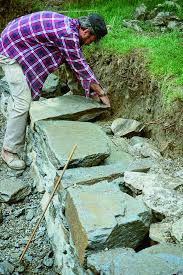 Building a retaining wall on a slope. Build A Dry Stacked Stone Retaining Wall Finegardening