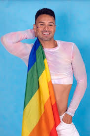 Gay guy smiling with the pride flag over his shoulder blue background |  Premium Photo