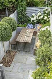 White end and side walls, a row of trees, a rectangle of decking, a raised circular mound of lawn tangential to it, a mass of herbaceous plants in the end corner, the whole is a complete unit, graceful and formal. Fulham Slim Subtle Garden Design London Courtyard Gardens Design Garden Design London Small Courtyard Gardens