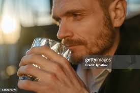 Close Up Of A Sad Thoughtful Man Drinking Whiskey On A Roof During The Dawn  High-Res Stock Photo