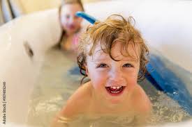 Caucasian children playing with mermaid tail in bath Stock Photo