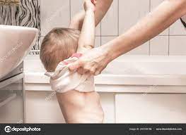 Mom undresses the happy baby girl for taking a bath Stock Photo by  ©Tagwaran 257259186