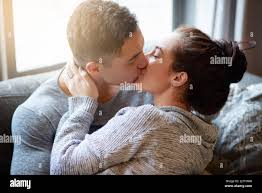 Baci appassionati sul divano. Scatto di una giovane coppia affettuosa  baciante sul divano a casa Foto stock - Alamy