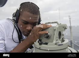 US Navy Seaman Recruit uses a needle gun to remove paint as he works