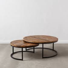 Two round iron and wood coffee tables sit on a gray and tan patterned rug in front of cane and rattan accent chairs placed facing a light gray couch topped with white and black pillows and positioned beside a round end table topped with a white pierced lamp. Set Of Two Coffee Tables Black Brown Mueble4you