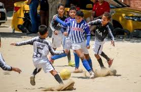 Niños pequeños en entrenamiento juegan fútbol. Cambia El Saludo Pero El Futbol Sigue En Los Barrios A Pesar Del Coronavirus