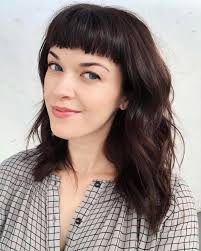 Choppy, wavy hair that cascades past the shoulders provides a distinct contrast to the extremely short baby bangs that are cut straight across the forehead. How To Pull Off Baby Bangs In The Real World Thefashionspot