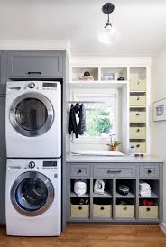Laundry room designed with a white sliding door on an oil rubbed bronze rail showcasing gray cement tiles and stacked front load washer and dryer. Neat Laundry Room Grey Laundry Rooms Laundry Room Design Laundry Room Storage