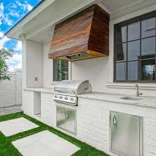 The limestone farmhouse sink is a salvaged piece and is surrounded by matching countertops. White Stucco Outdoor Kitchen Hood Design Ideas
