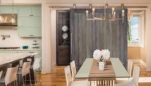 Dining room features a long vintage wooden dining table with french metal dining chairs, white linen captain dining chairs, a beige dining bench, a silver leaf etagere, and black windows over black french doors with blush pink curtains. Oversized Doors Large Wooden Monster Doors From Simpson