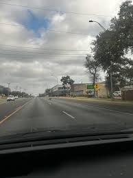 Small black dog with pink collar and tags running east