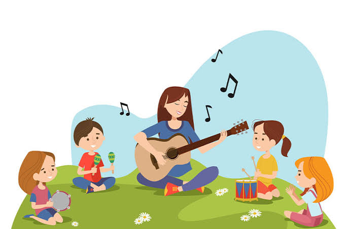 "Ilustração de uma professora e quatro crianças em um círculo de música no gramado. A professora, ao centro, toca um violão e sorri. À sua esquerda, um menino de vermelho segura dois maracás e uma menina de rosa segura um pandeiro. À sua direita, uma menina de amarelo bate um pequeno tambor e outra menina de laranja bate palmas. Notas musicais flutuam no ar e margaridas decoram a grama, sob um céu azul claro."