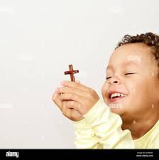 little boy praying to God with holy cross and being religious stock image  with hands held together praying in church