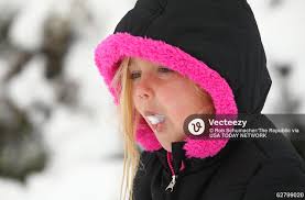 Ashlee Martin, age 5 enjoys a bite of desert snow after a winter storm  brought six inches of snow. 62799020 Editorial Image