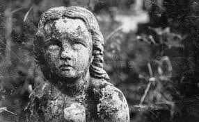 Dirty and Retro Styled Image of an Ancient Stone Statue of Sad Little Angel  with Broken Wings Praying As Symbol of Sorrow, Sadness Stock Photo
