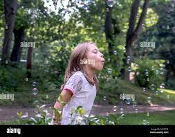 Süße kleine Mädchen bläst floating Blasen wie Sie treiben Vergangenheit  Stockfotografie - Alamy