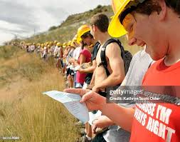 Aaron Mull from Milliken, CO, right, reads and sings the school song...  News Photo