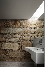 A gorgeous contemporary bathroom done with rough stone walls covered with glass and a wooden bathtub. 61 Wonderful Stone Bathroom Designs Digsdigs