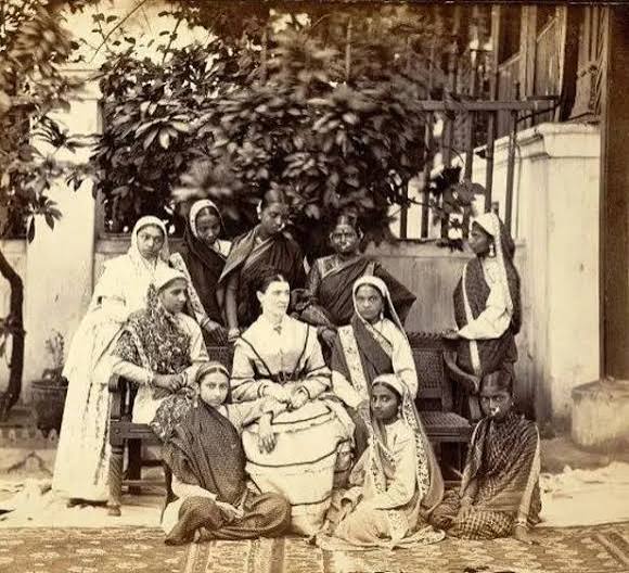 An old photographic image of an English 'memsahib' with some Indian ladies, British India, circa late 19th century. Can anyone please identify the location more precisely? Somebody told me it could be