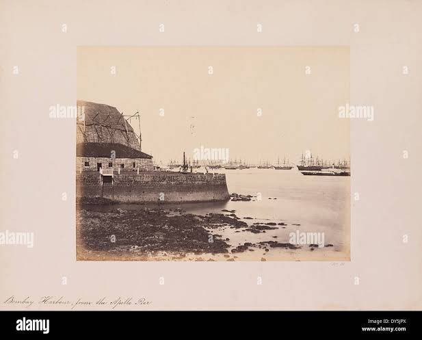 The view of Bombay Harbour from the Apollo Pier captures the busy waterfront with sailing ships, docks, and piers. It highlights the bustling maritime activities of one of India's major ports in