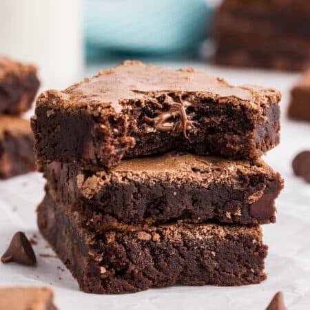 Fudgy Brownies stacked on a plate with a glass of milk