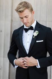 Spring or summer weddings at the beach call for lightweight outfits in linen. Boutonniere Style Black Notch Lapel Tuxedo With A Black Bow Tie And A Simple White Floral Bouto Wedding Suits Men Black Groom Suit Black Groomsmen Attire Black