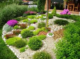 Blumenbeet Mit Steinen Gartendeko Kleine Busche Lila Blumen Holzmobel Aussenbereiche Ziegelhaus Vorgarten Pflanzen Steingarten Gestalten Blumenbeet Ideen