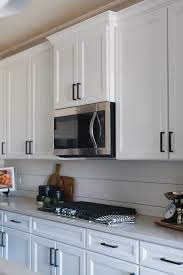 White Shaker Kitchen Cabinets Accented With Oil Rubbed Bronze Pulls And An Off White White Shaker Kitchen Cabinets White Shaker Kitchen Shaker Kitchen Cabinets