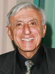 Jamie Farr Nobody but nobody would ever have predicted that a grocer's son  from Toledo, OH, would some day become internationally famous for parading  around in dresses and flowered hats. But that