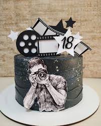 Black textured cake with a photographer cutout, film strip toppers, and stars for an 18th birthday.