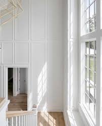 Custom Millwork In The Stairwell And Entryway Wainscoting In White Modern Geometric Gold Chandelier In The Stairw Home Indoor Design Entryway Table Styling