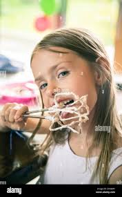 Portrait of little girl licking whipped cream from stirrer Stock Photo