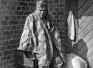 A Red Army soldier, covered by a German raincoat, sits on ...