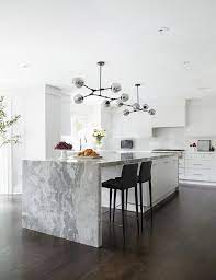 An island can add whatever you need more of to your kitchen, whether it is work space, storage, seating or all three.having table or bar seating is great for. Marble Waterfall Island With Sleek Black Chairs Modern Kitchen