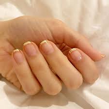 Female legs with bare feet and hands with french manicure and pedicure on white towel in spa salon and decorative pink flower. Modern French Manicures What Does The French Manicure Look Like Today