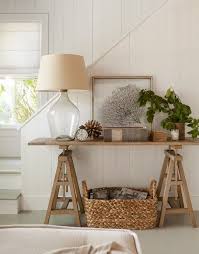 Sawhorse Style Console Table Bottle Lamp Alarm Clock Plant Old Books Woven Basket In 2020 Decor Cottage Decor Beach House Interior