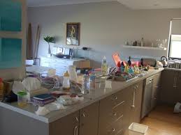 Messy home kitchen during remodeling with cabinet doors open cluttered with paint cans, tools and dirty rags, canned ceiling light. The Very Bad Mother S Blog The On Going House Work Messy Kitchen House Corner Desk