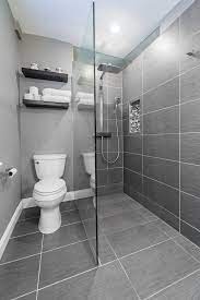 Unlike painting, tiling isn't as quick and easy as it looks. Small Bathroom With Grey Flooring Grey Tiles In Shower Wall Grey Painted Wall In White Toilet Ar Bathroom Design Layout Bathroom Design Small Bathroom Layout