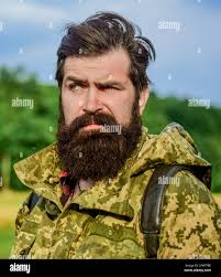 Poacher in the Forest. Bearded hunter man holding gun and walking in  forest. Hunting Licenses. Hunter with shotgun gun