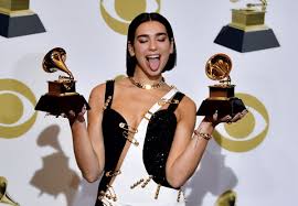 About the actual dress itself, the black evening gown was made from silk and lycra strategically held together with oversized novelty gold safety pins to reveal daring cutouts, and held up at a plunging neckline with slimline straps and more pins. How Dua Lipa S Safety Pin Dress At The Grammys Channelled Liz Hurley Flipboard