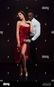 beautiful seductive interracial couple in formal wear posing isolated on  black Stock Photo - Alamy