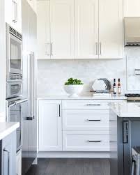Finishes in white, pale or warm woods and any shiny metals in the form of accessories, hardware or appliances will all look fabulous with your navy cabinets. White Shaker Panel Cabinets Dark Grey Island Marble Backsplash Modern White Kitchen Cabinets Kitchen Cabinets And Backsplash Kitchen Cabinet Remodel