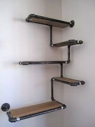 The wood shelves, almost the entire length of the wall, slide down on each pipe and rest on the t joint. Plumbers Pipe Shelving