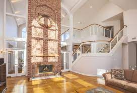A white fireplace and ceiling beams balance dark walnut floors. How To Decorate Interiors With High Ceilings