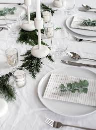 A Minimalist Table Setting With An Evergreen Garland White Candles And Eucalyp Christmas Table Centerpieces Holiday Table Decorations Christmas Table Settings