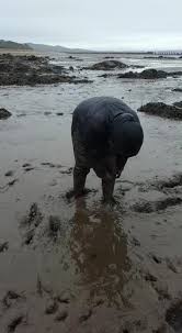 woman gets stuck in mud at beach