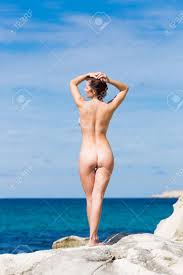 Mulher Nua Com Os Braços Levantados Banhos De Sol Na Hora Da Manhã Na Pedra  Costeira Olhando Para Longe, Vista Traseira Foto Royalty Free, Gravuras,  Imagens e Banco de fotografias. Image 121836155