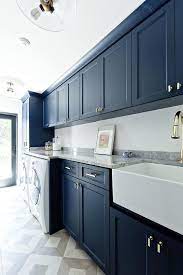 Crafted from manufactured wood in a navy blue hue, this piece features a traditional cabinet front with three drawers and three doors adorned by a decorative wood design on their glass fronts. Navy Laundry Room Cabinets Laundry Room Storage Shelves Blue Laundry Rooms Laundry Cabinets