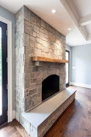 natural gray stone fireplace with reclaimed wood mantel and arched firebox opening grey white fireplaces stacked record storage ideas